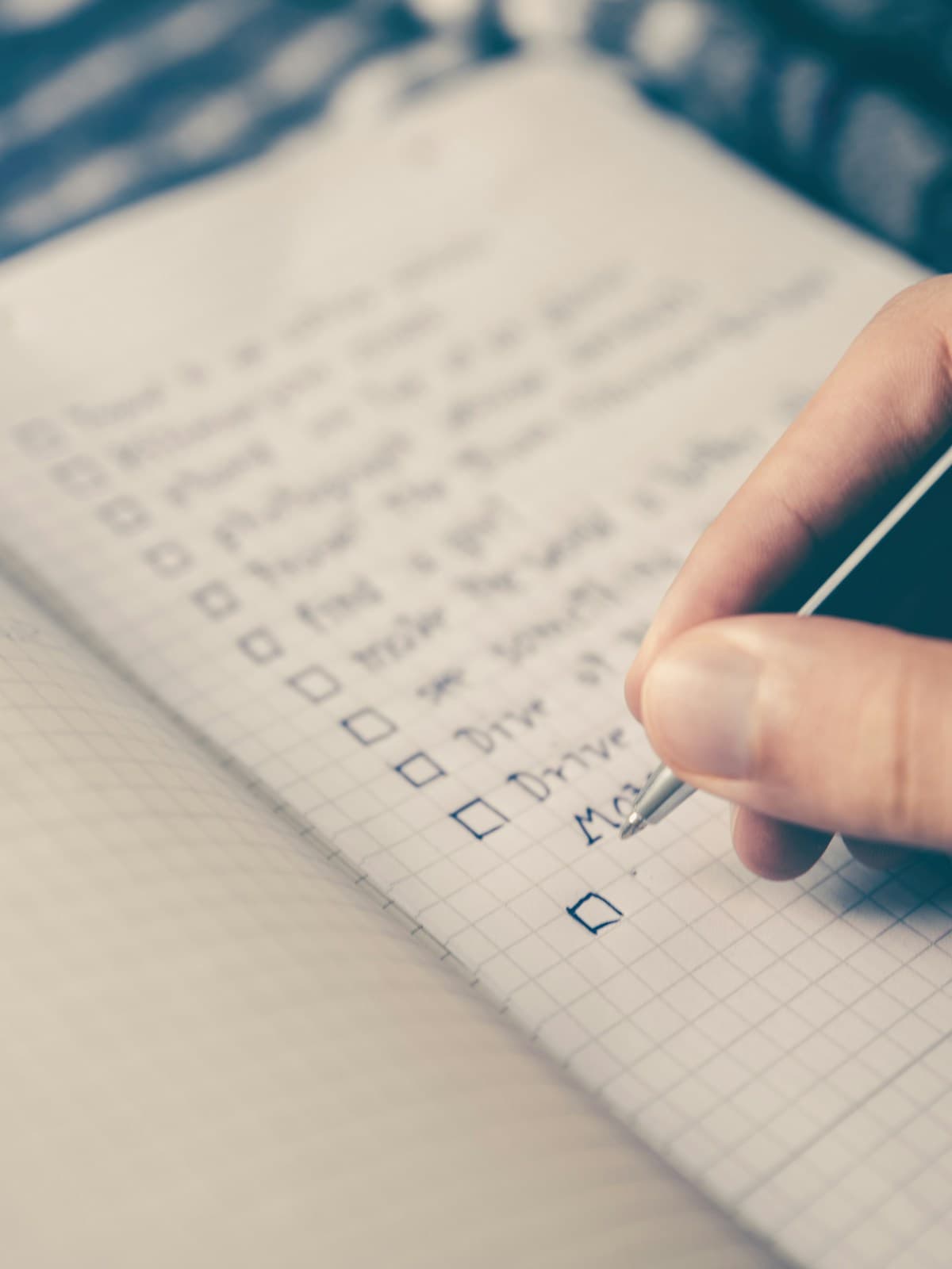 A hand marking progress on a handwritten checklist