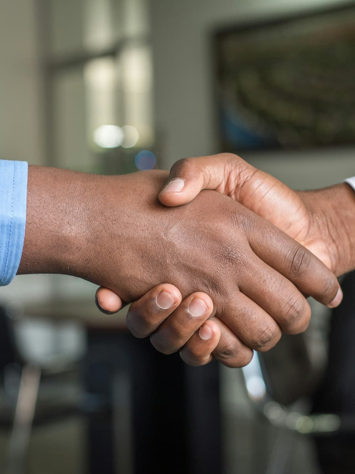 Two people greeting one another with a supportive handshake
